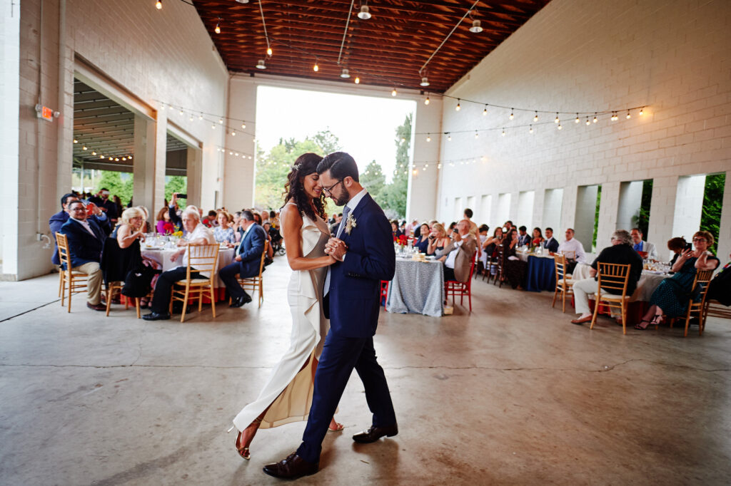 A newly married couple dances their first dance in a cool, modern building. 
