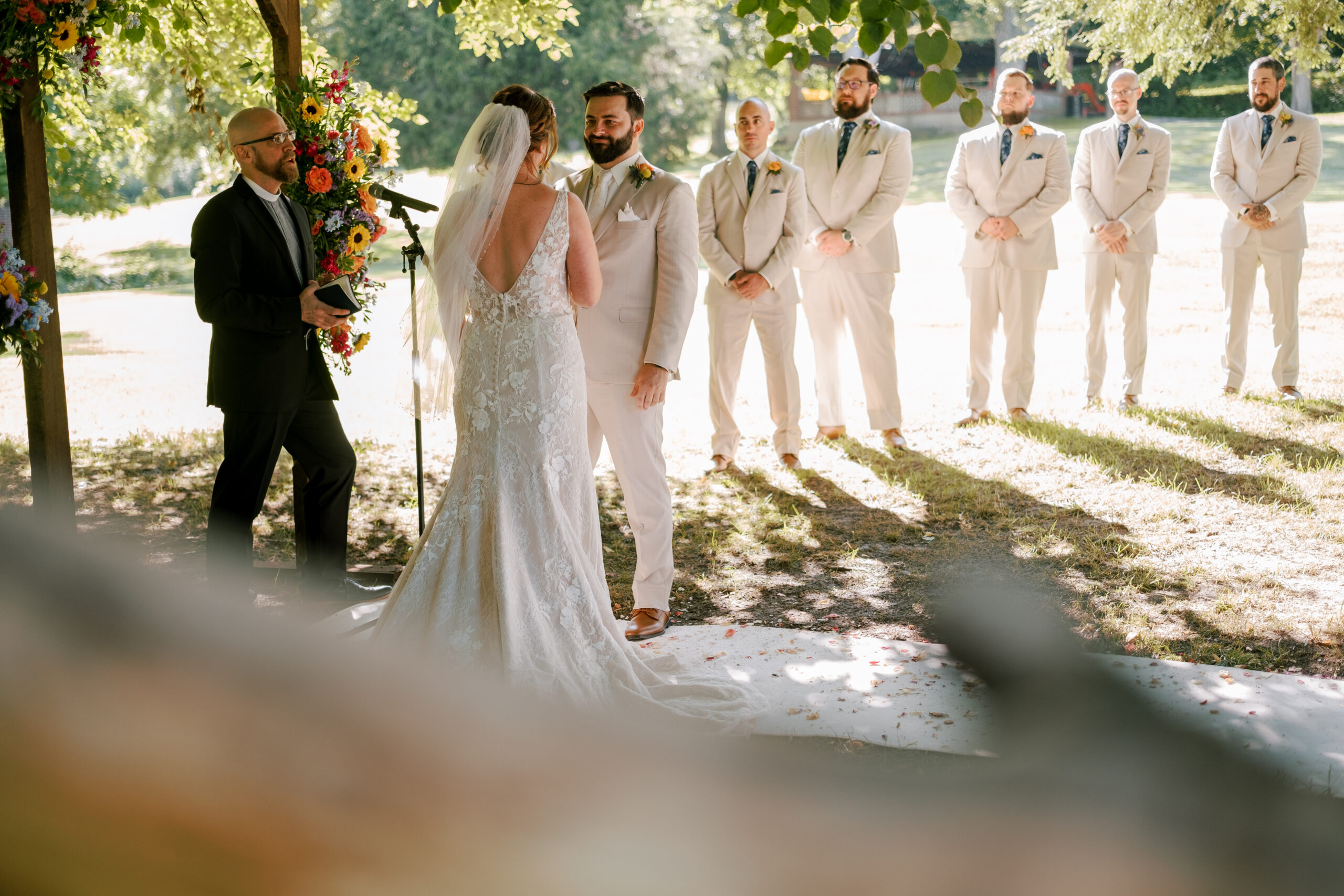 A couple gets married under a tree in a rustic outdoor wedding.