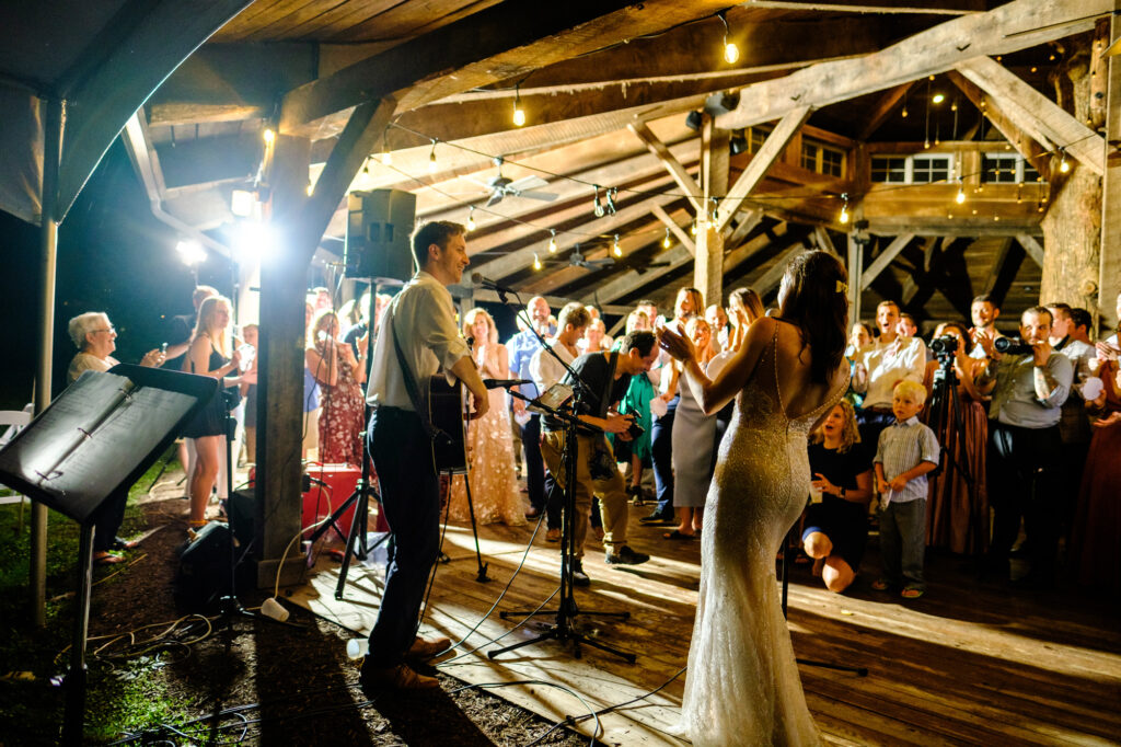 A couple plays music at their wedding reception while their guests sing along. 