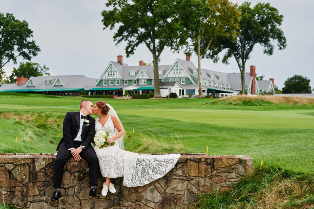 A couple poses for a portrait on a beautiful golf course after their outdoor wedding. 