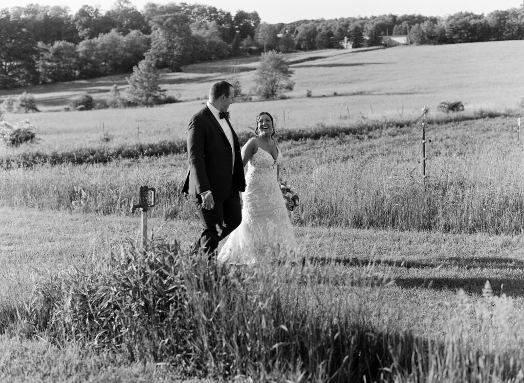 A happy couple walks hand in hand around the grounds at Lingrow Farm, one of the best barn wedding venues in Pennsylvania. 